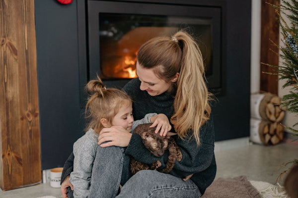 Mum and daughter sitting by the fireplace at home in winter