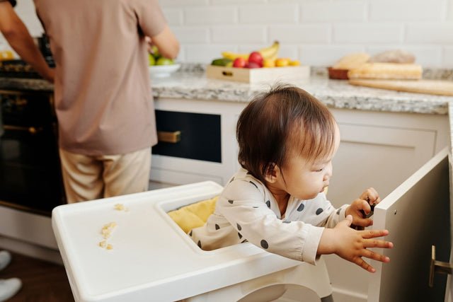 Toddler reaching to open a kitchen cupboard door