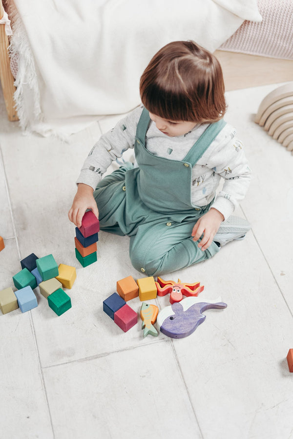 Toddler sitting on the floor playing with small building blocks