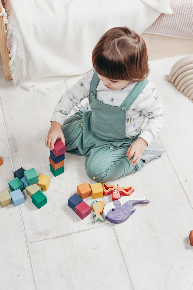 Toddler sitting on the floor playing with small building blocks