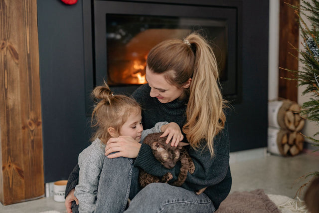 Mum and daughter sitting by the fireplace at home in winter